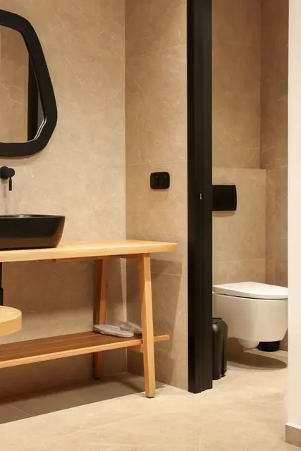 Black-framed mirror above a wooden vanity with the toilet beside