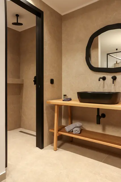 Bathroom with vanity and walk-in shower in a beige stone finish