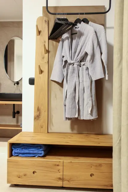 Wooden storage unit with a bathrobe and towels beside the bathroom