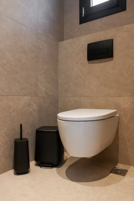 En-suite toilet with black bin and toilet brush