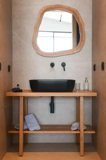 En-suite bathroom with an organic wooden mirror and black basin
