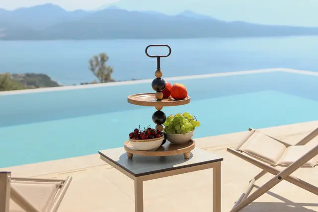 Fruit platter on a table beside the pool with the sea beyond