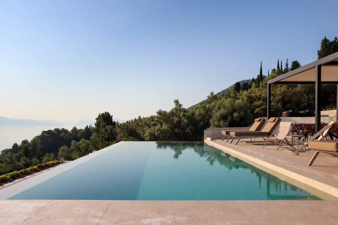 Infinity-style pool appearing to merge with the sea and wooded hills