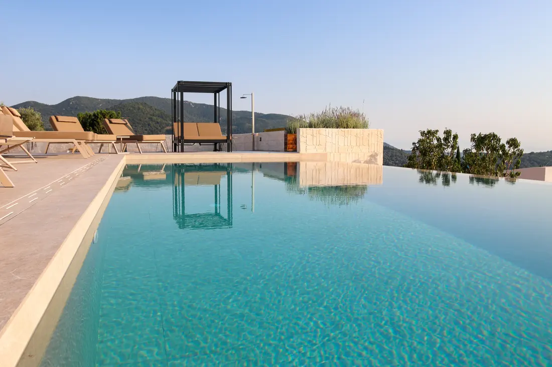 Infinity-style pool and sunbeds with mountain views in soft morning light