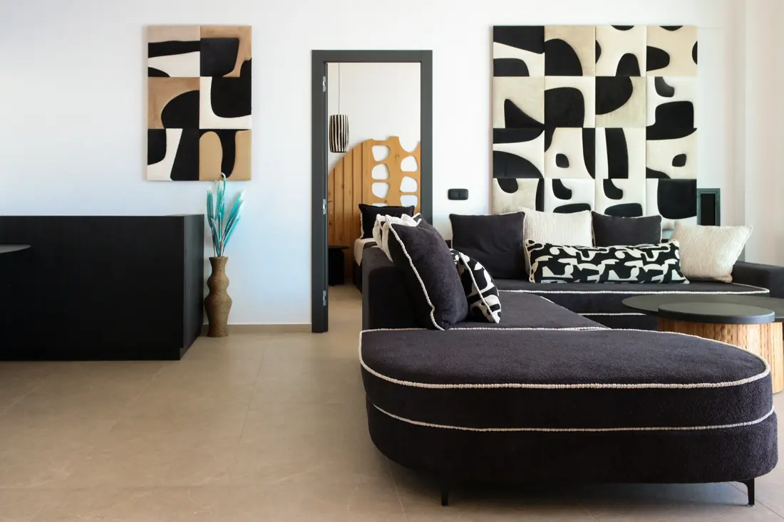 Living room with a curved dark sofa and bold black-and-cream artwork