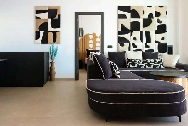 Living room with a curved dark sofa and bold black-and-cream artwork