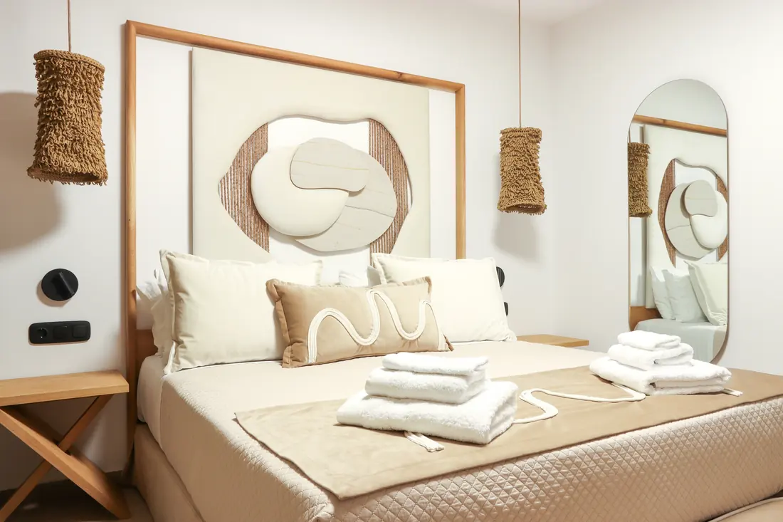 Double bed with folded towels and a sculpted headboard panel