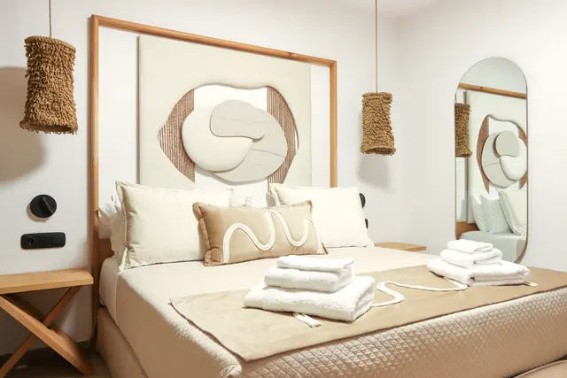 Double bed with folded towels and a sculpted headboard panel