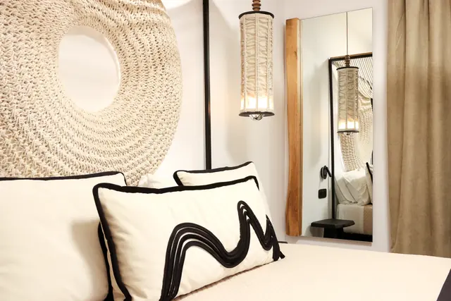 Bedroom cushion with a bold black wave pattern beside a woven lamp