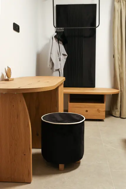 Bedroom corner with a wooden desk, black laundry basket and clothes rack
