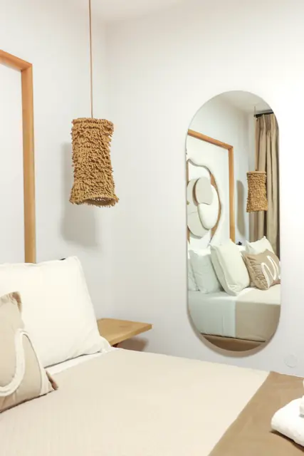 Bedroom detail with an oval mirror and a woven pendant lamp