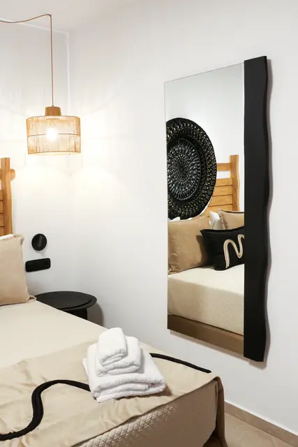 Full-length mirror, pendant light and bed with folded towels