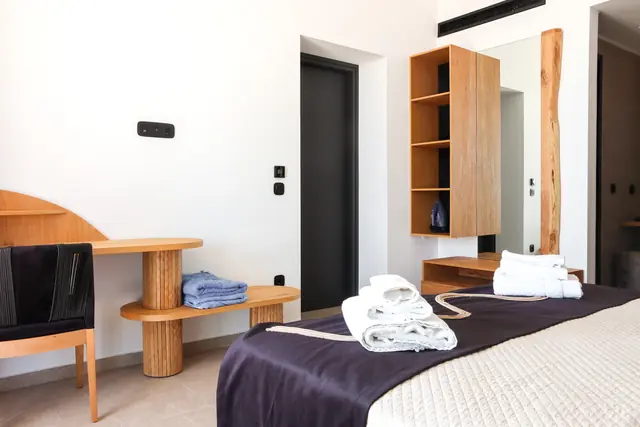 Main bedroom with desk, shelving and folded towels on the bed