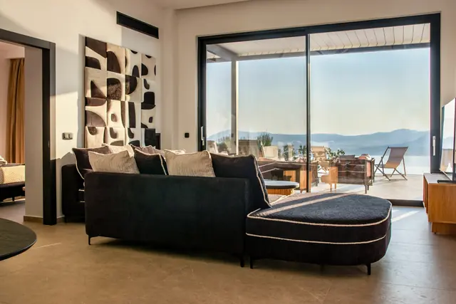 Open-plan living area with a dark sofa and sea views through large glass doors