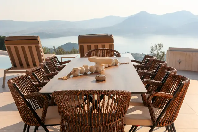 Large outdoor dining table with rattan chairs and sea views
