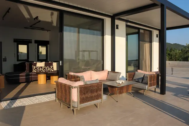 Outdoor lounge area with sofas and armchairs under the terrace pergola
